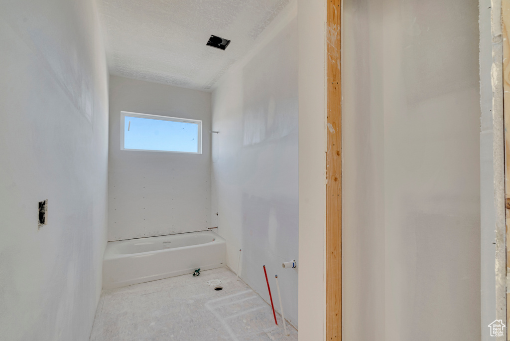 Bathroom with a bathing tub and a textured ceiling