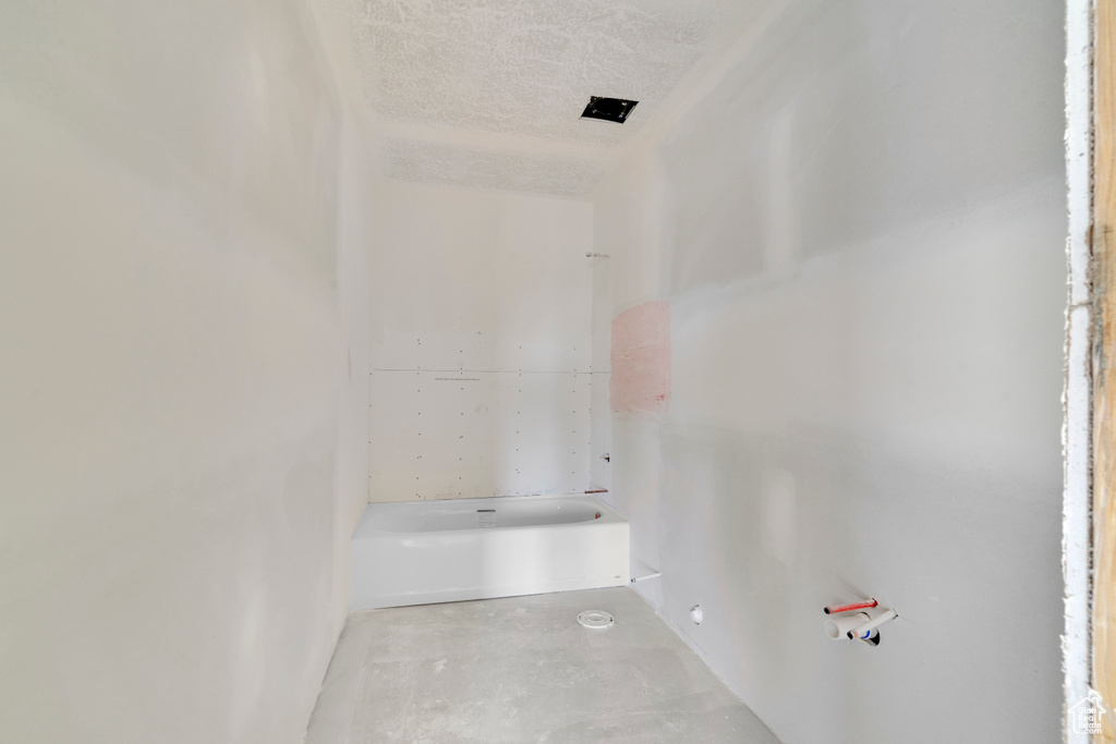 Bathroom with a textured ceiling and concrete floors