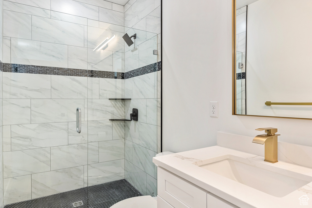 Bathroom featuring vanity, a shower with door, and toilet