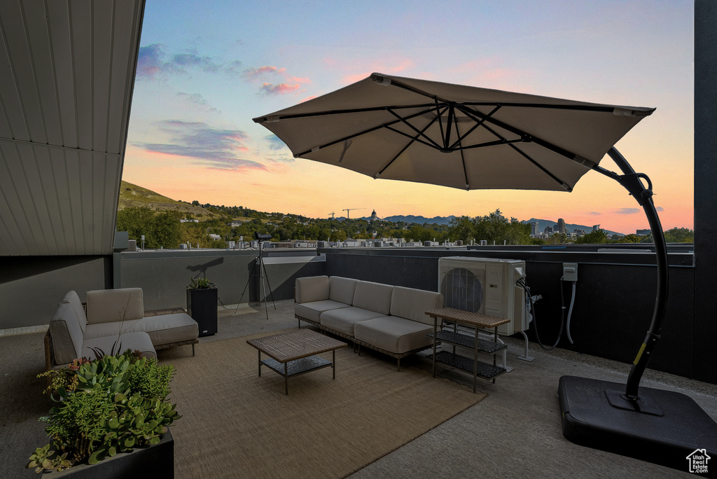 Patio terrace at dusk with a balcony, an outdoor living space, a mountain view, and ac unit