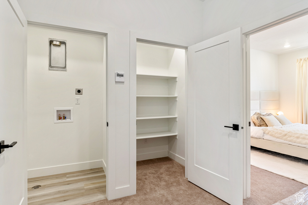 Interior space with hookup for a washing machine, hookup for an electric dryer, and light colored carpet