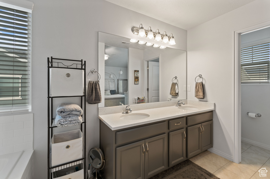 Bathroom with ceiling fan, vanity, tile patterned flooring, and a bath