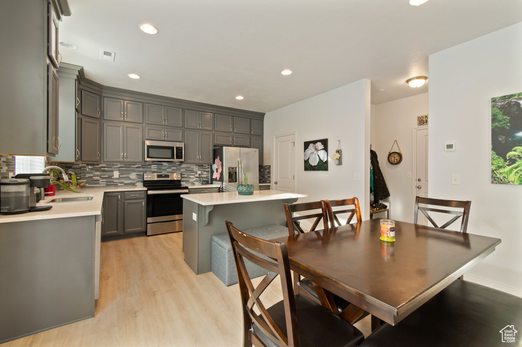 Kitchen with a kitchen island, sink, light hardwood / wood-style flooring, appliances with stainless steel finishes, and gray cabinets