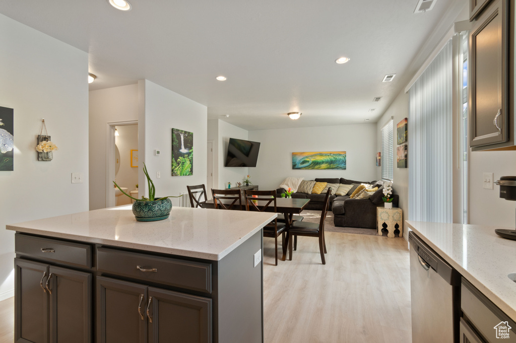 Kitchen featuring light stone countertops, a kitchen island, light hardwood / wood-style flooring, and stainless steel dishwasher