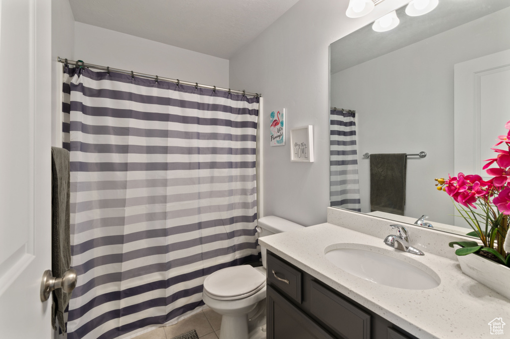 Bathroom with tile patterned floors, a shower with shower curtain, vanity, and toilet