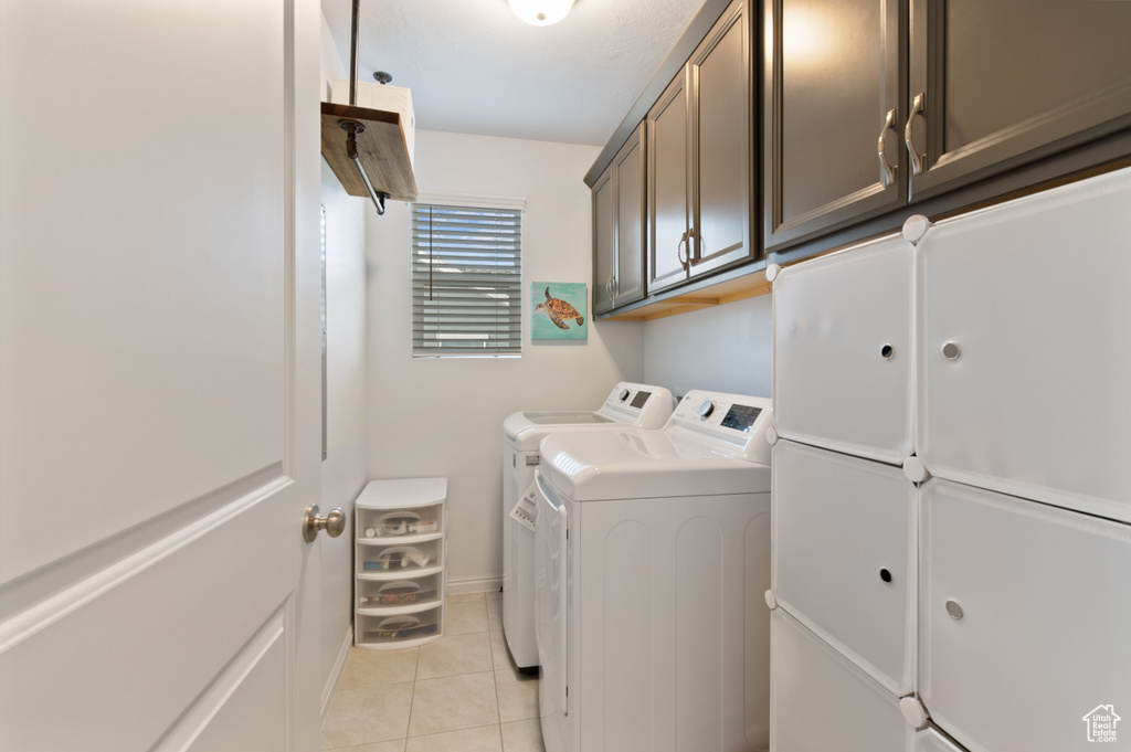 Clothes washing area with cabinets, separate washer and dryer, and light tile patterned floors