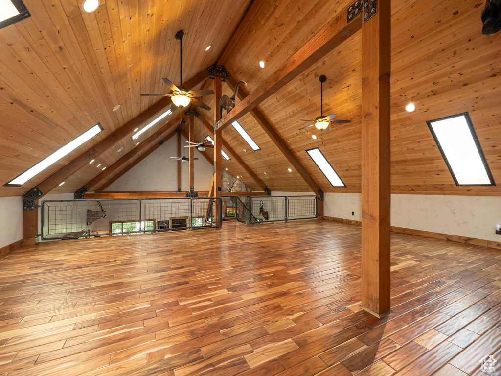 Additional living space with beam ceiling, light hardwood / wood-style flooring, and ceiling fan