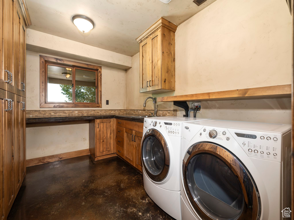 Clothes washing area with cabinets, sink, and washing machine and dryer