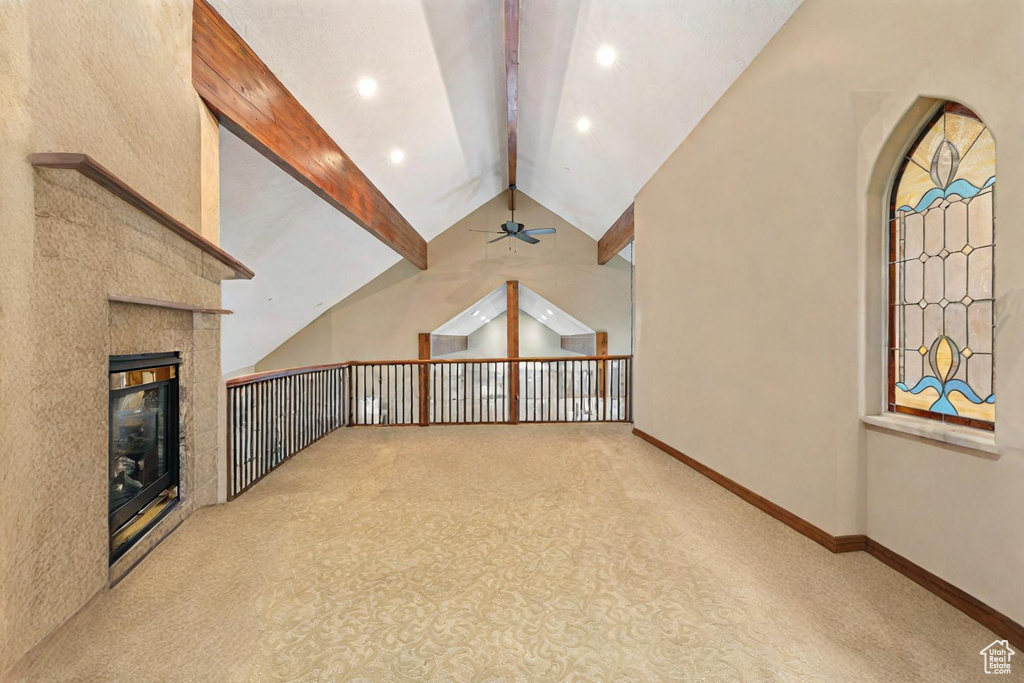 Bonus room featuring a fireplace, light colored carpet, vaulted ceiling with beams, and ceiling fan