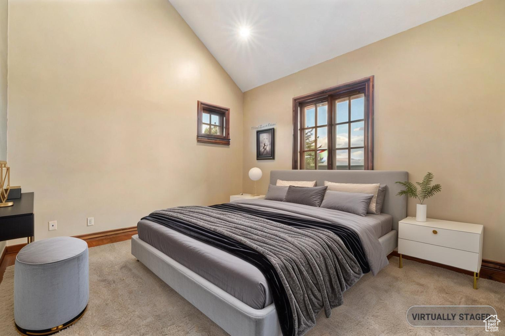 Bedroom with high vaulted ceiling and light colored carpet