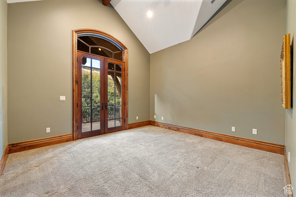 Carpeted spare room featuring french doors and high vaulted ceiling