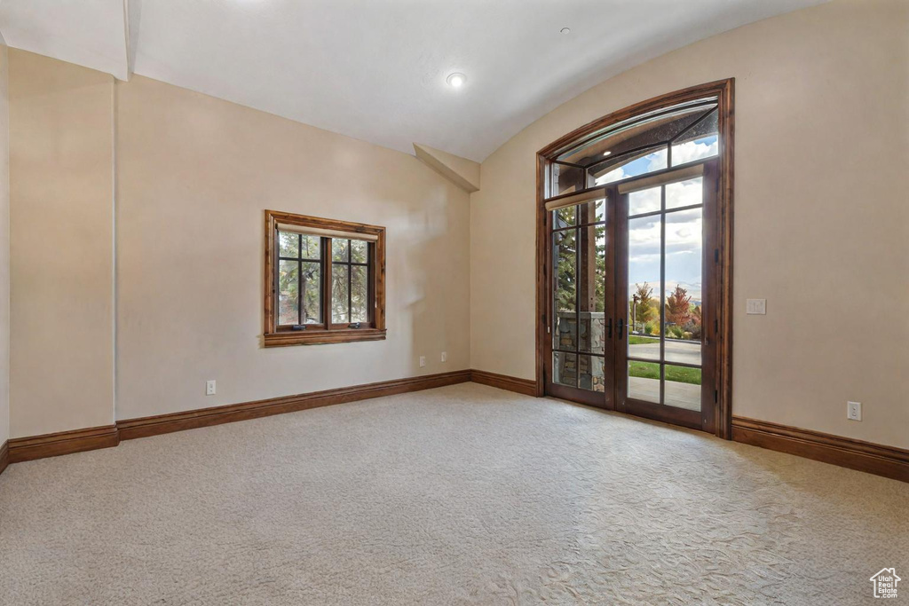 Carpeted spare room with vaulted ceiling and french doors