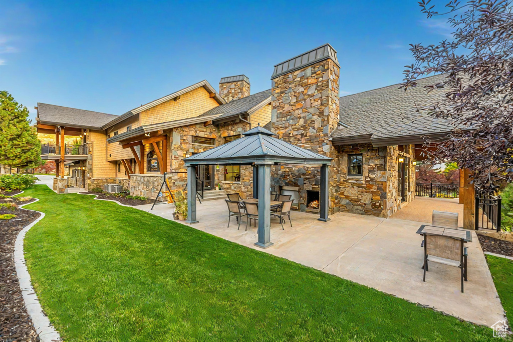 Rear view of house featuring a gazebo, central air condition unit, a patio, and a lawn