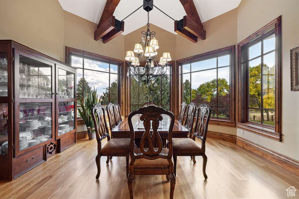 Dining room with a notable chandelier, beamed ceiling, plenty of natural light, and light hardwood / wood-style flooring