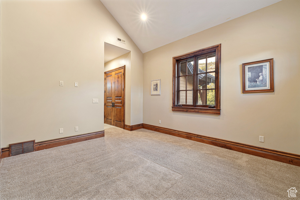 Carpeted empty room with high vaulted ceiling