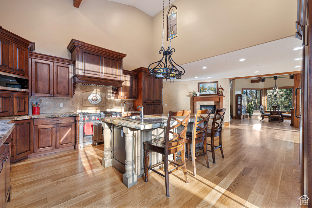 Kitchen with light stone counters, light hardwood / wood-style floors, hanging light fixtures, and a kitchen breakfast bar