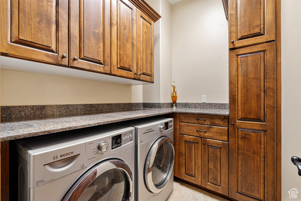 Laundry area featuring washer and clothes dryer and cabinets