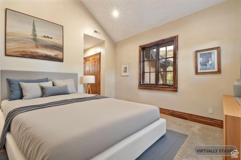 Carpeted bedroom with a closet and vaulted ceiling