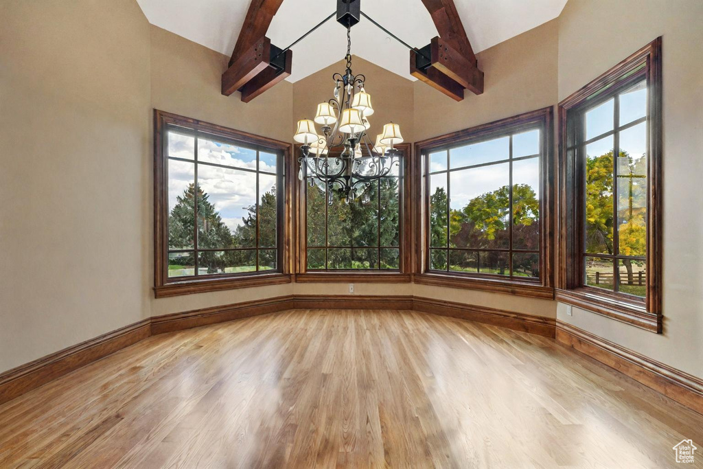 Unfurnished dining area featuring beam ceiling, light hardwood / wood-style flooring, and a wealth of natural light