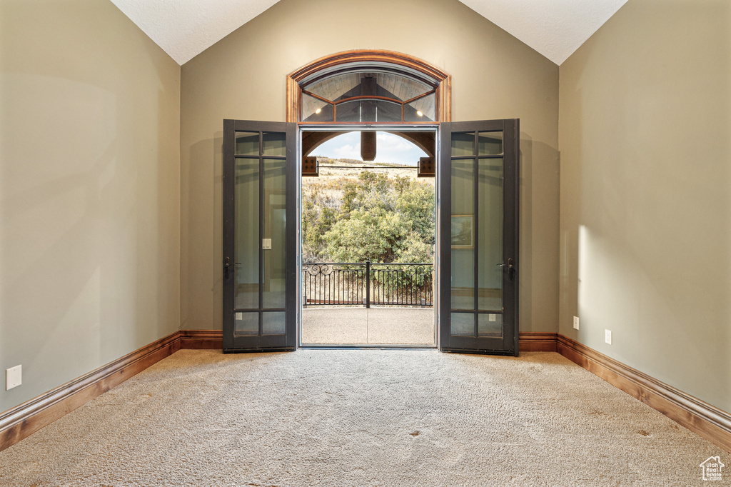 Carpeted entryway with french doors and vaulted ceiling