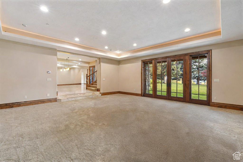 Unfurnished room with light colored carpet and a raised ceiling