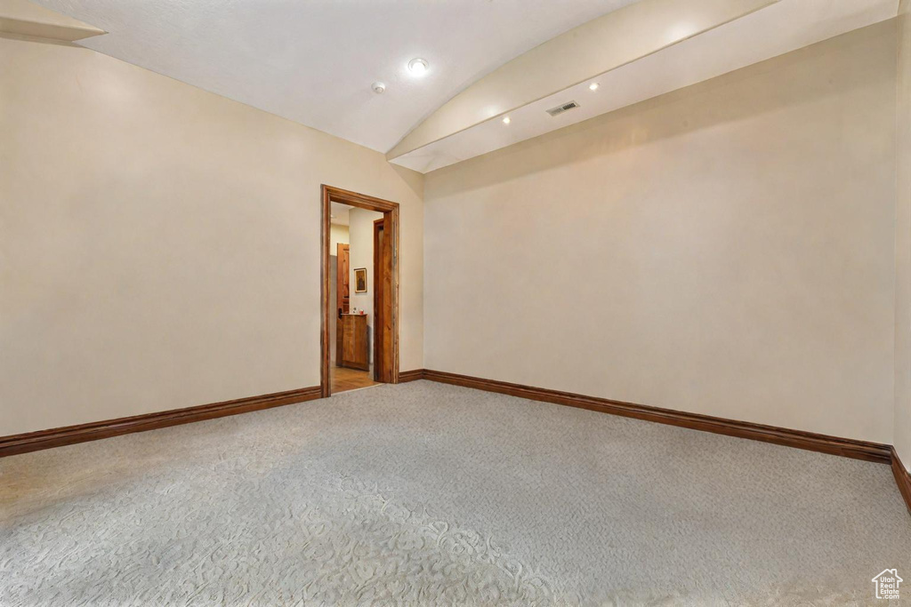 Empty room with vaulted ceiling and carpet