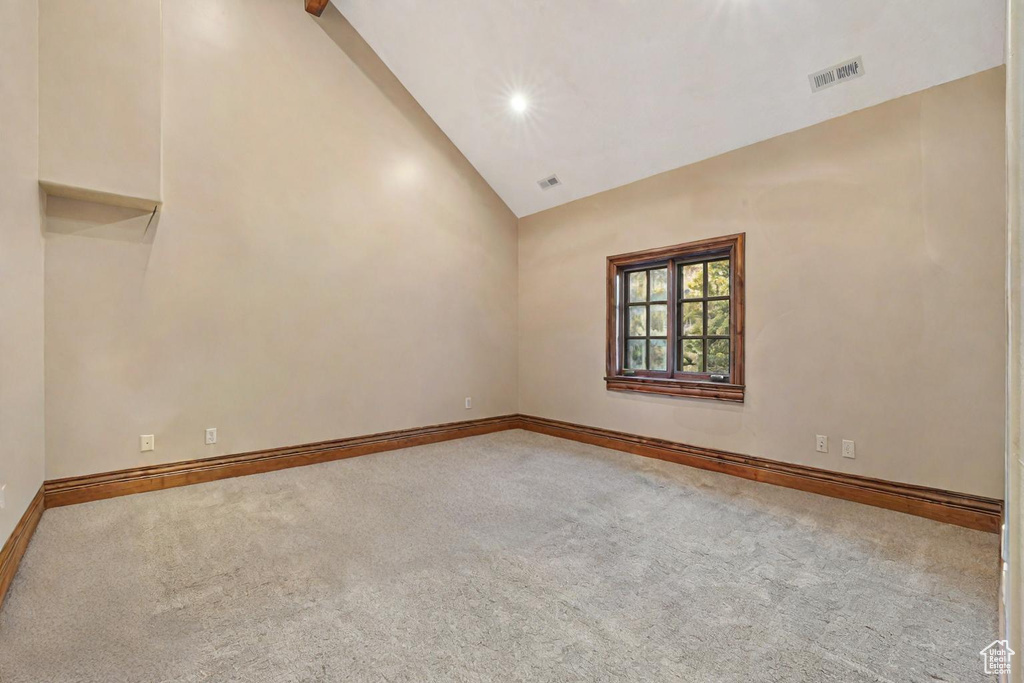 Spare room featuring carpet floors and high vaulted ceiling