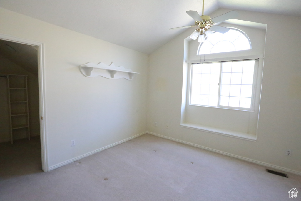 Carpeted empty room featuring ceiling fan and lofted ceiling