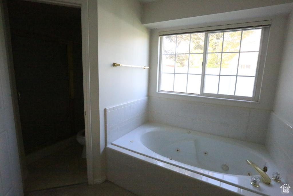 Bathroom with a relaxing tiled tub and toilet