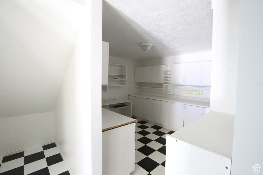 Kitchen featuring a textured ceiling and white cabinets