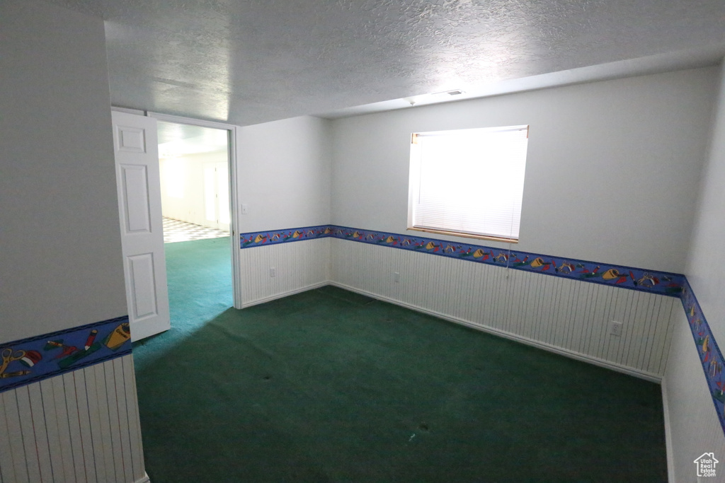 Spare room featuring a textured ceiling and dark colored carpet