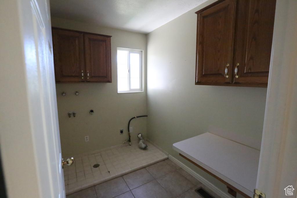 Clothes washing area featuring light tile patterned flooring, hookup for a washing machine, gas dryer hookup, and cabinets