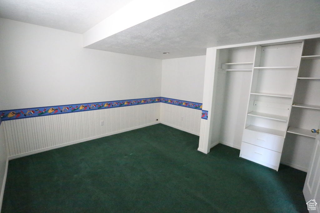 Interior space featuring dark carpet and a textured ceiling