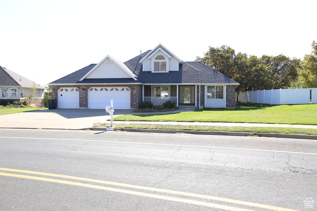 View of front of home with a garage, a front lawn, and covered porch