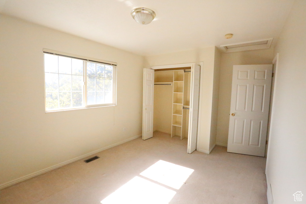 Unfurnished bedroom featuring light carpet and a closet