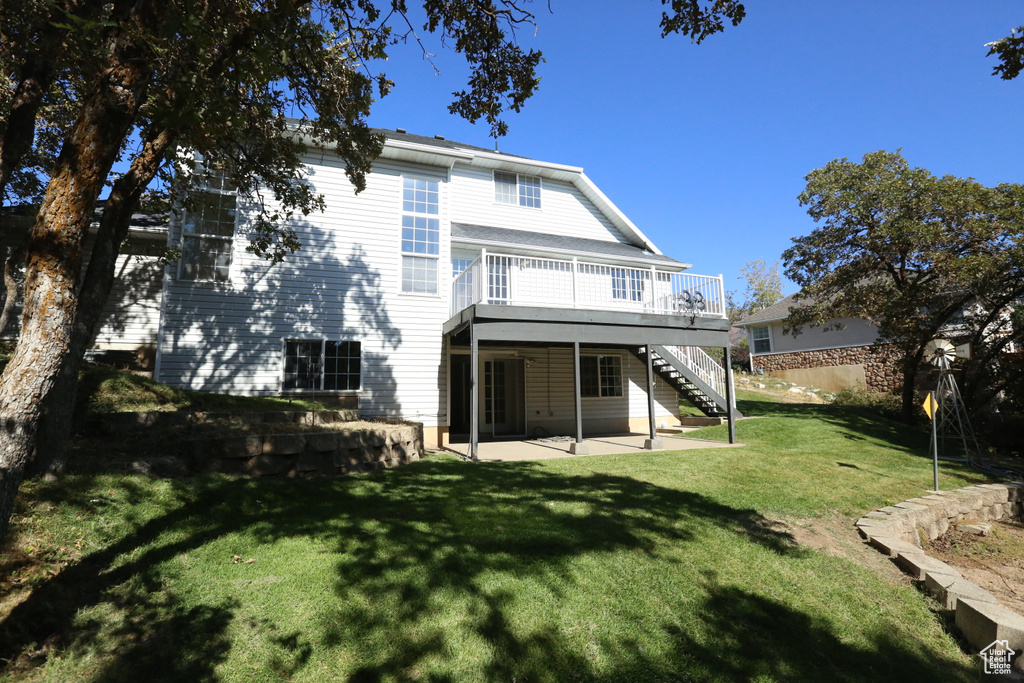 Rear view of property featuring a yard, a wooden deck, and a patio