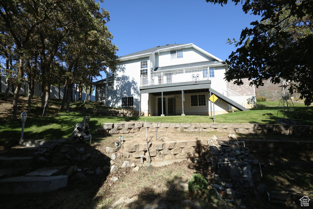 Back of property featuring a wooden deck and a lawn