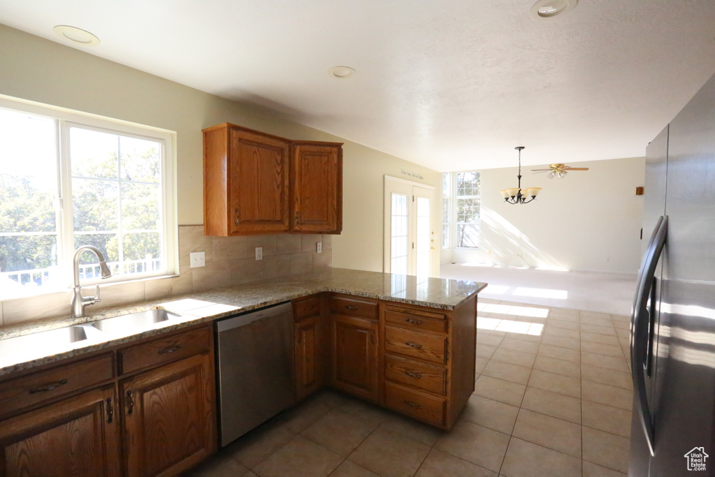 Kitchen with stainless steel appliances, kitchen peninsula, sink, and a wealth of natural light