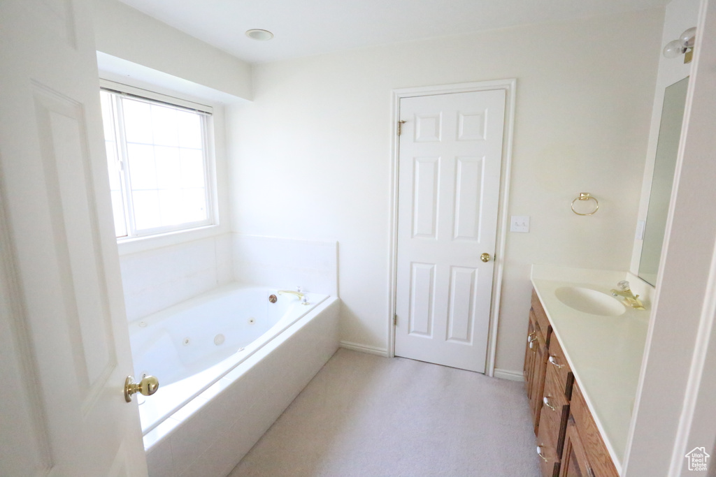 Bathroom featuring tiled tub and vanity