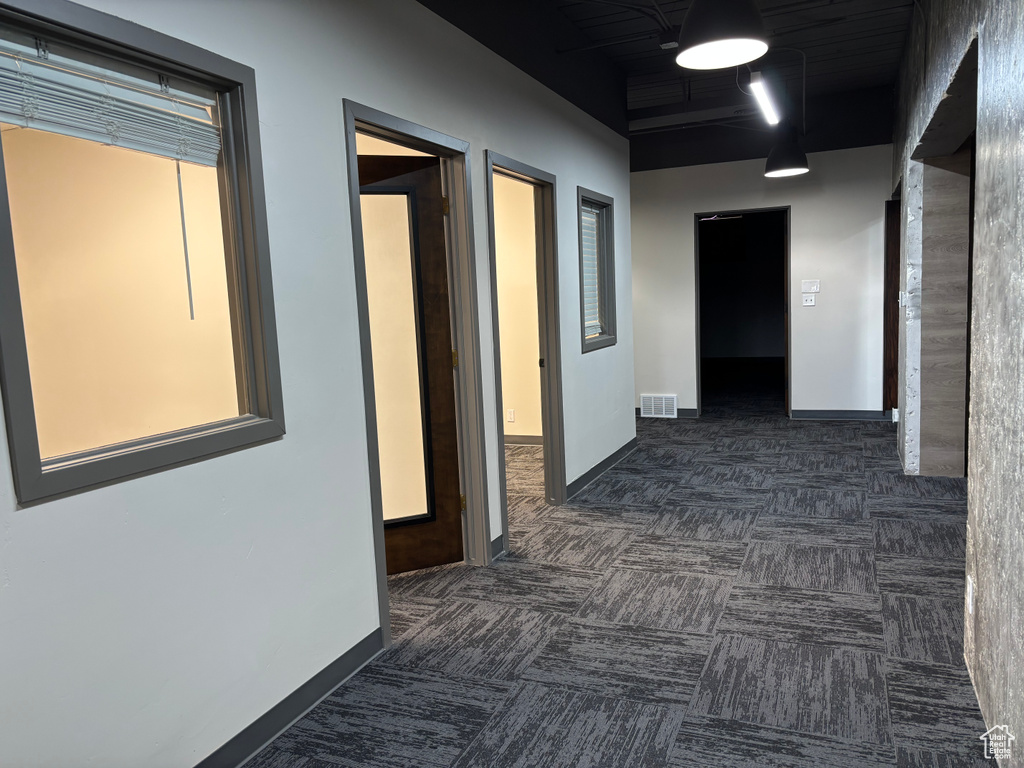 Hall with baseboards, carpet, and visible vents