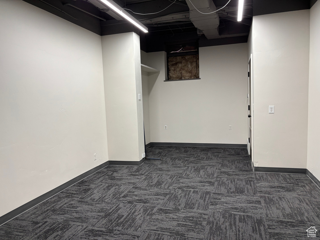 Interior space featuring baseboards and dark colored carpet