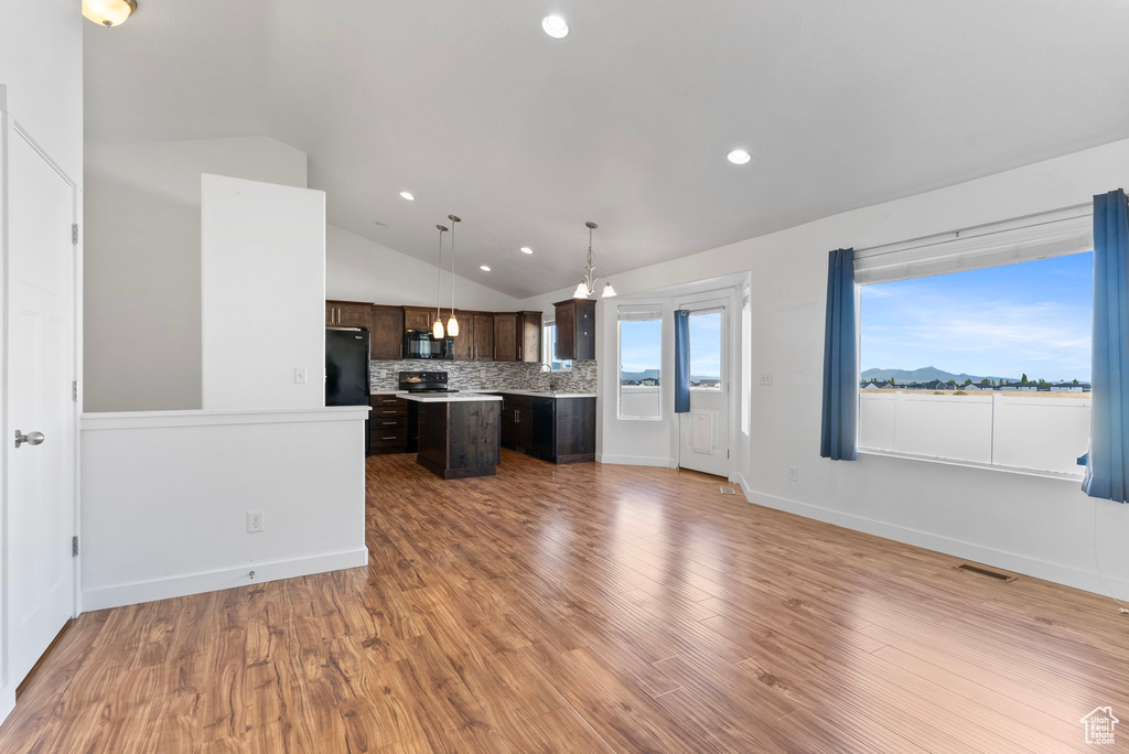 Kitchen with a kitchen island, dark brown cabinetry, vaulted ceiling, black appliances, and hardwood / wood-style flooring