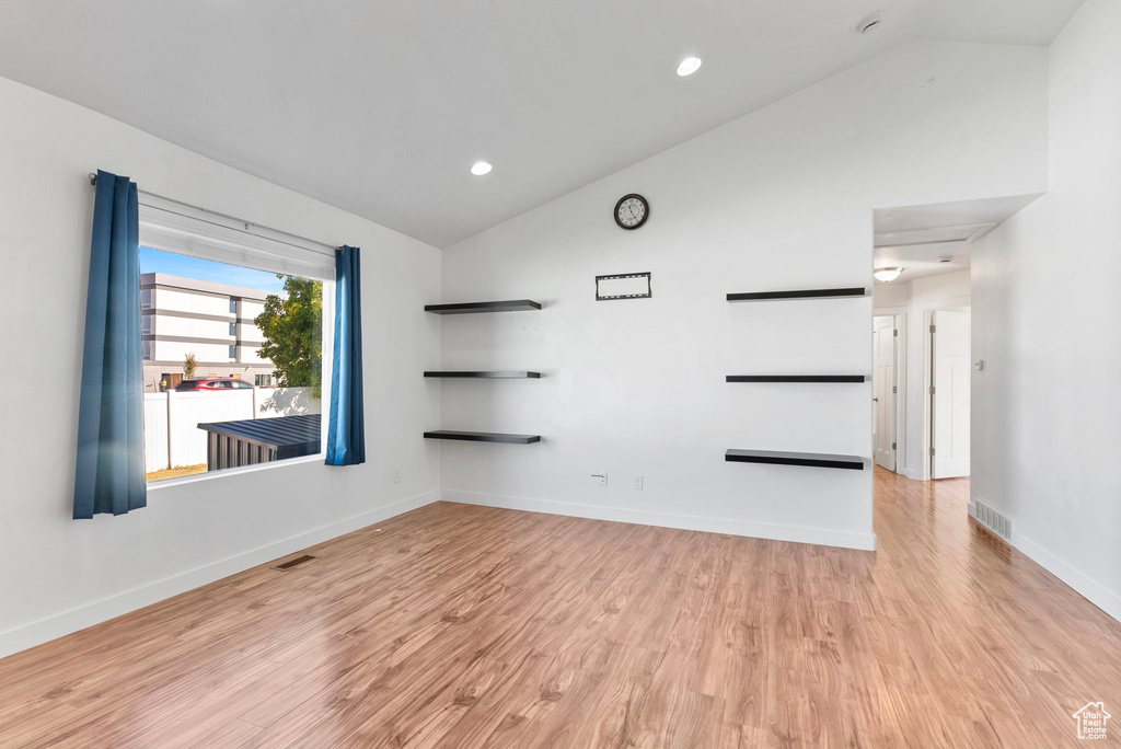 Unfurnished room with vaulted ceiling and light wood-type flooring