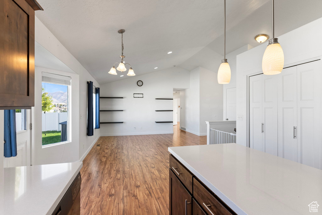 Kitchen with an inviting chandelier, hardwood / wood-style floors, dark brown cabinets, decorative light fixtures, and vaulted ceiling