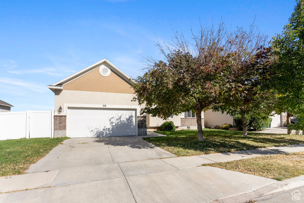 View of property hidden behind natural elements with a front yard and a garage