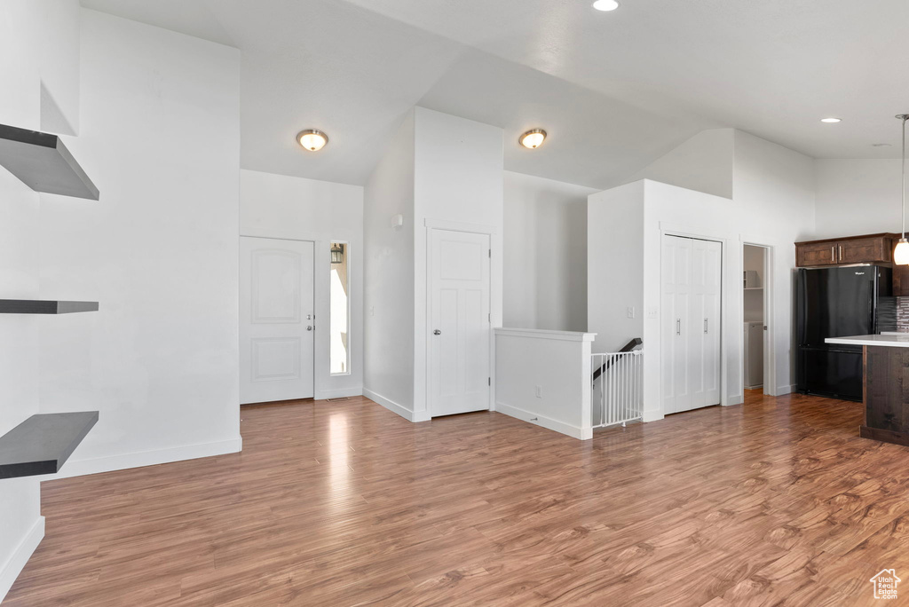 Unfurnished living room with light hardwood / wood-style flooring and high vaulted ceiling