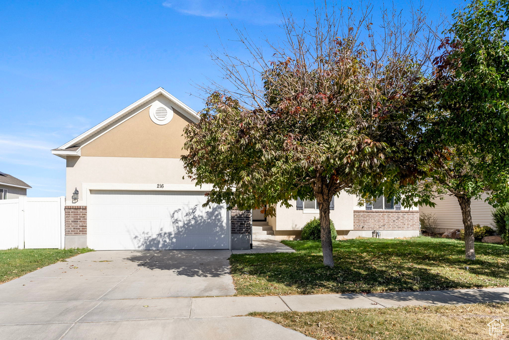 View of property hidden behind natural elements with a garage and a front yard