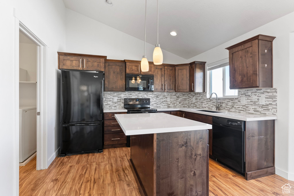 Kitchen with hanging light fixtures, sink, a kitchen island, black appliances, and vaulted ceiling