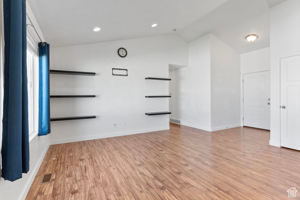 Spare room with light wood-type flooring and vaulted ceiling