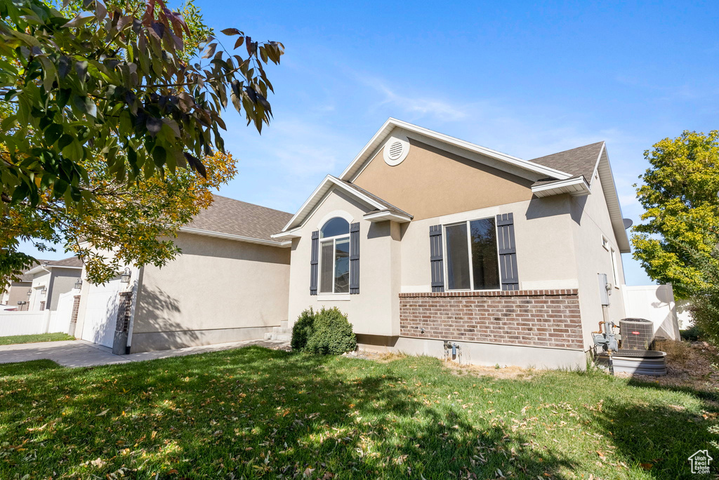 View of front of house with a front yard and central AC